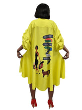 Load image into Gallery viewer, A woman shown from the back wearing a bright yellow oversized tunic dress with a colorful travel sign graphic and a woman carrying a suitcase printed on the back. She is wearing red high heels against a plain white background.